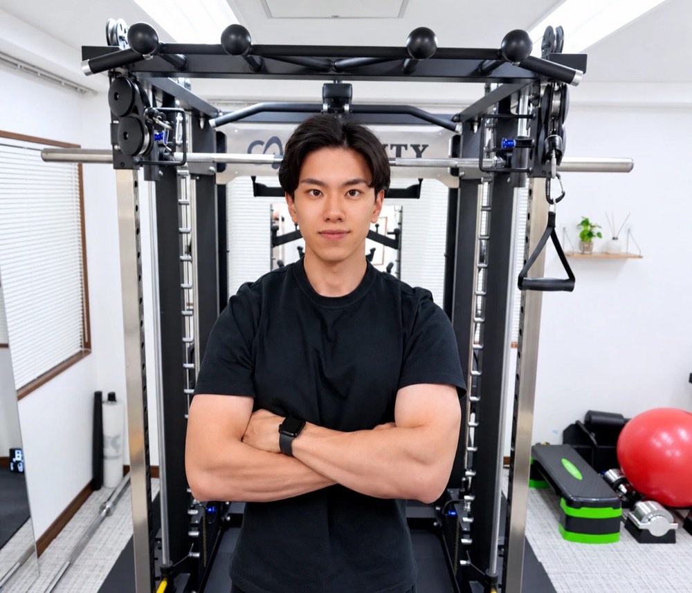 代表トレーナー 廣瀬健斗。ジムのマシンの前で腕を組んで立つ姿